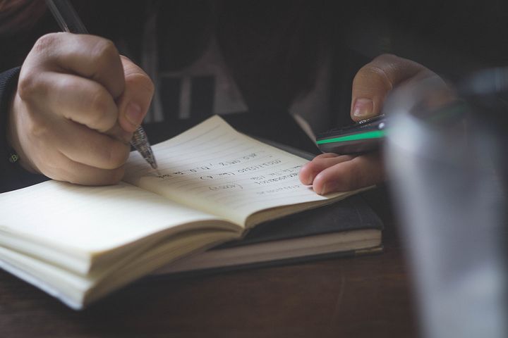Close up shot of a person writing in a notebook.