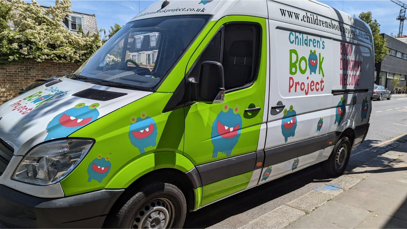 Image of a green and white van with a large logo for 'Children's book project'.