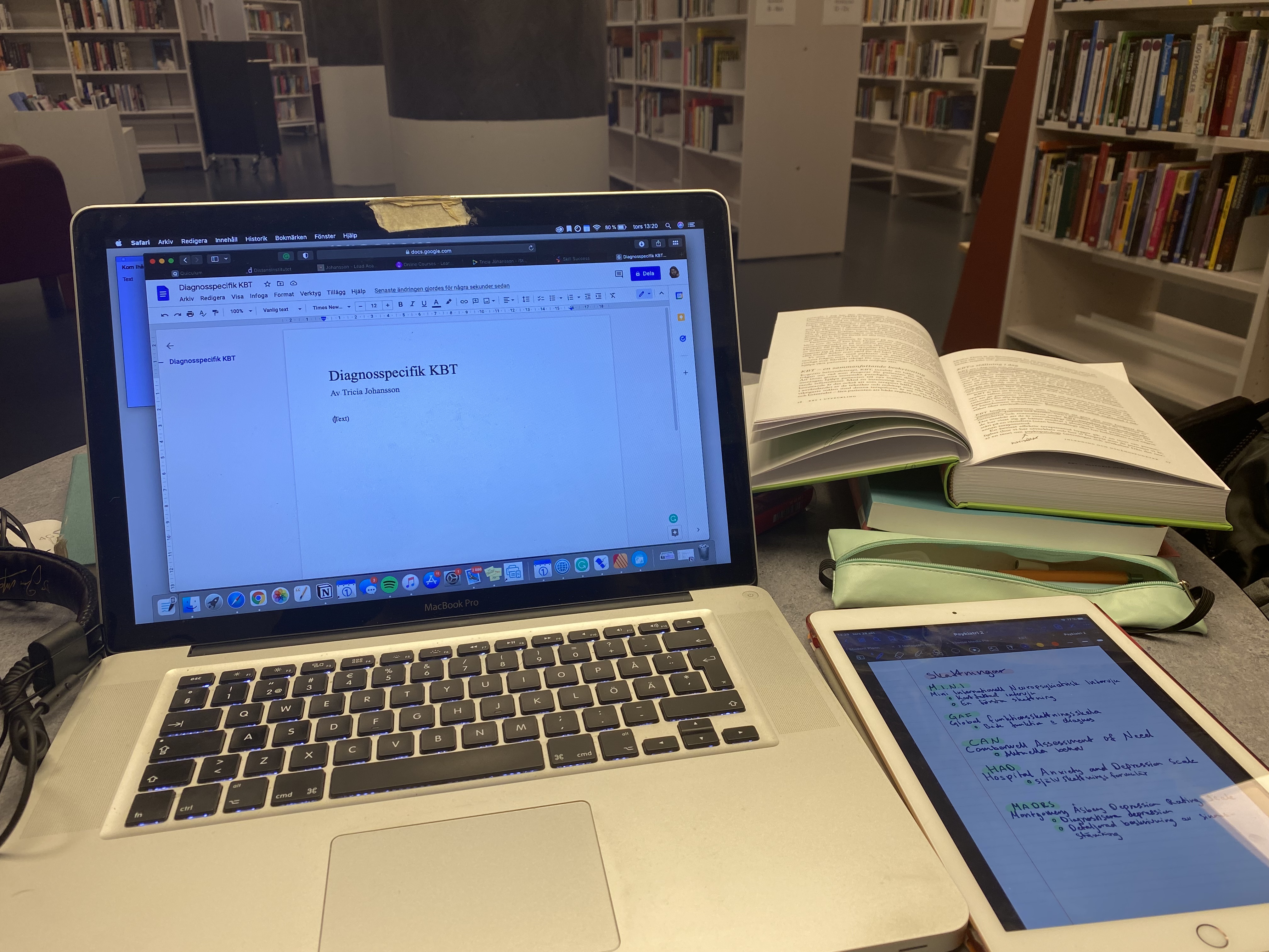 A open laptop, phone and open book on a study desk.