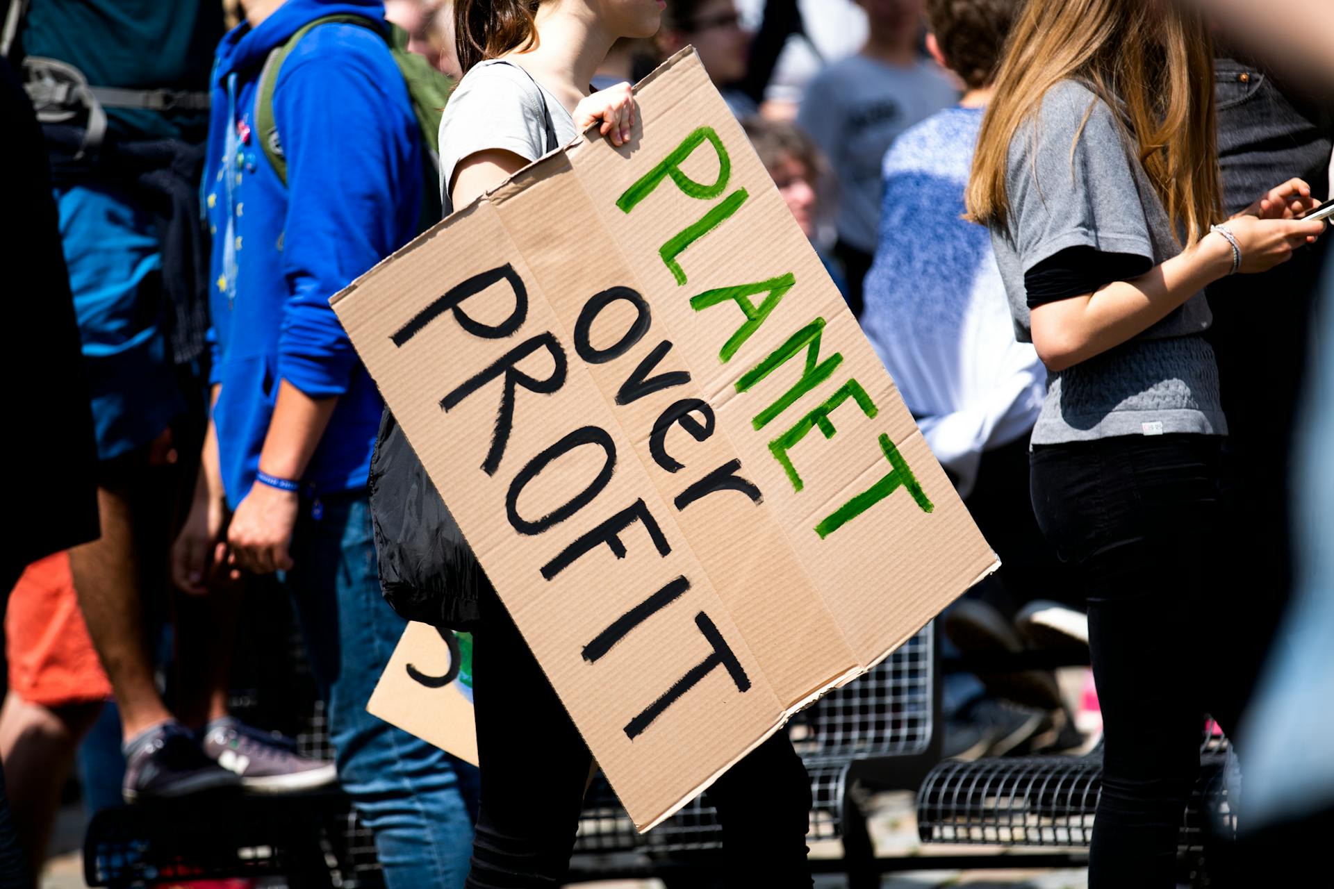 A group of people on a protest – one is holding a sign saying 'Planet over profit'.