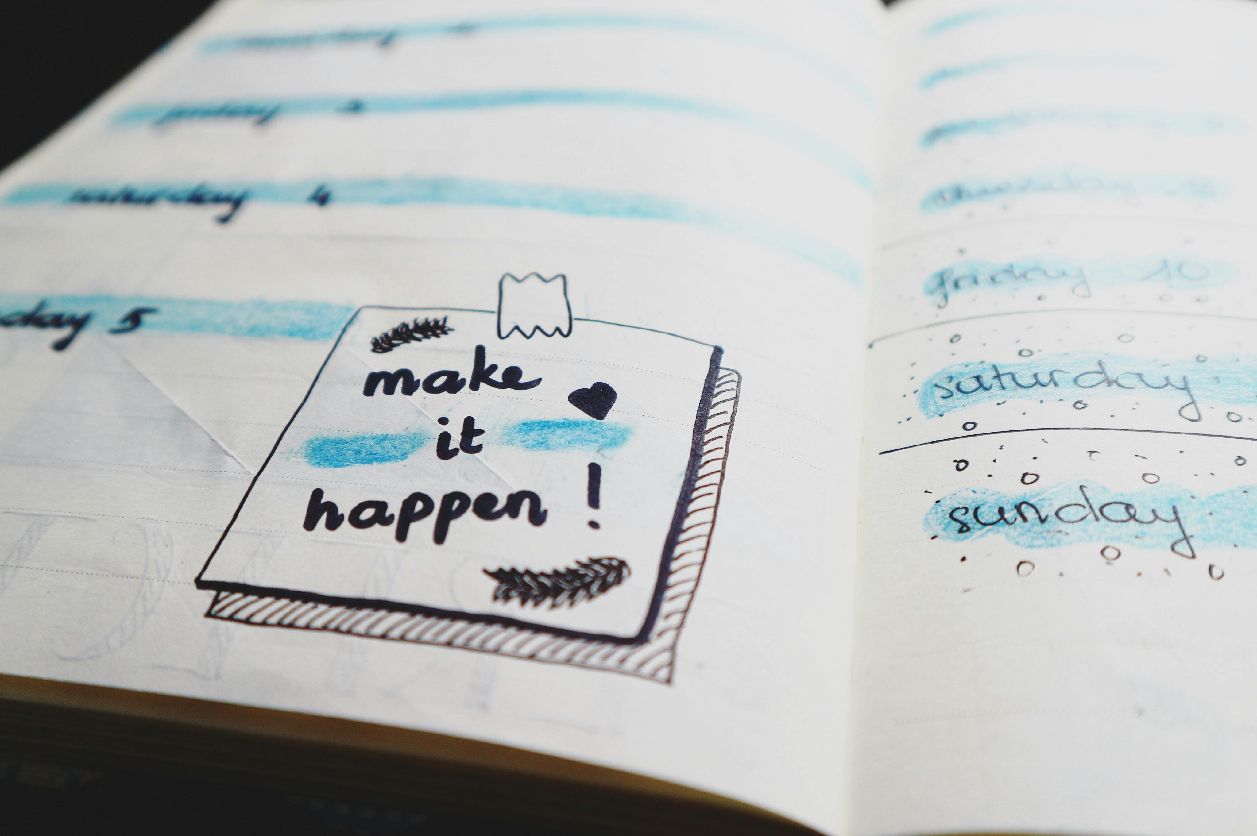 Open notebook with a drawing of a post-it note saying 'Make it happen!'