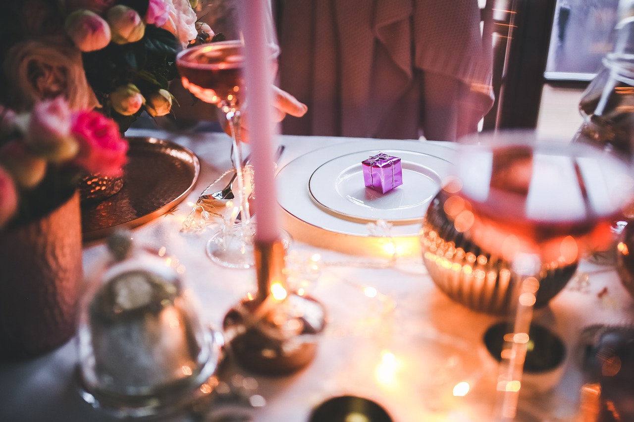 Photograph of a dining table set up for Christmas dinner with candles, decorations, and glasses of wine.