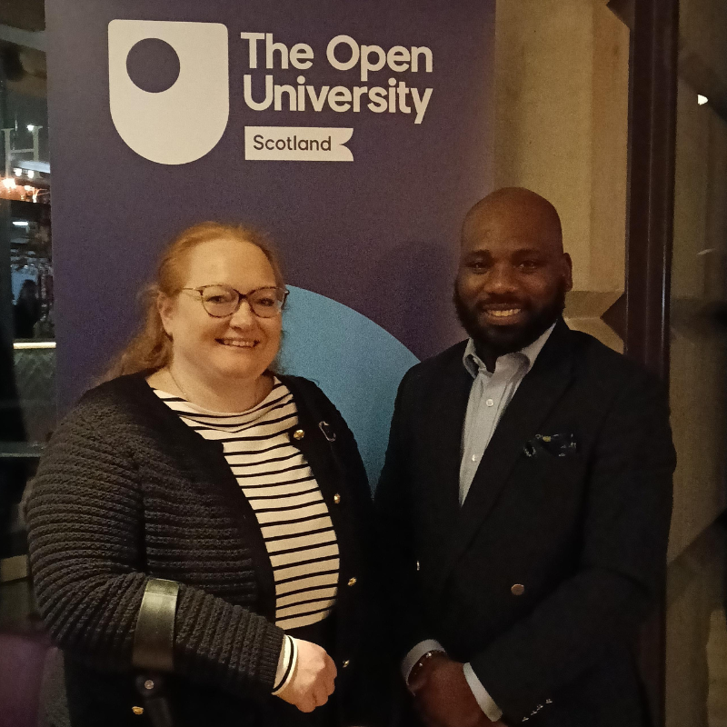 Andrew Kolapo and Natalie Baker standing by an OU Scotland banner.