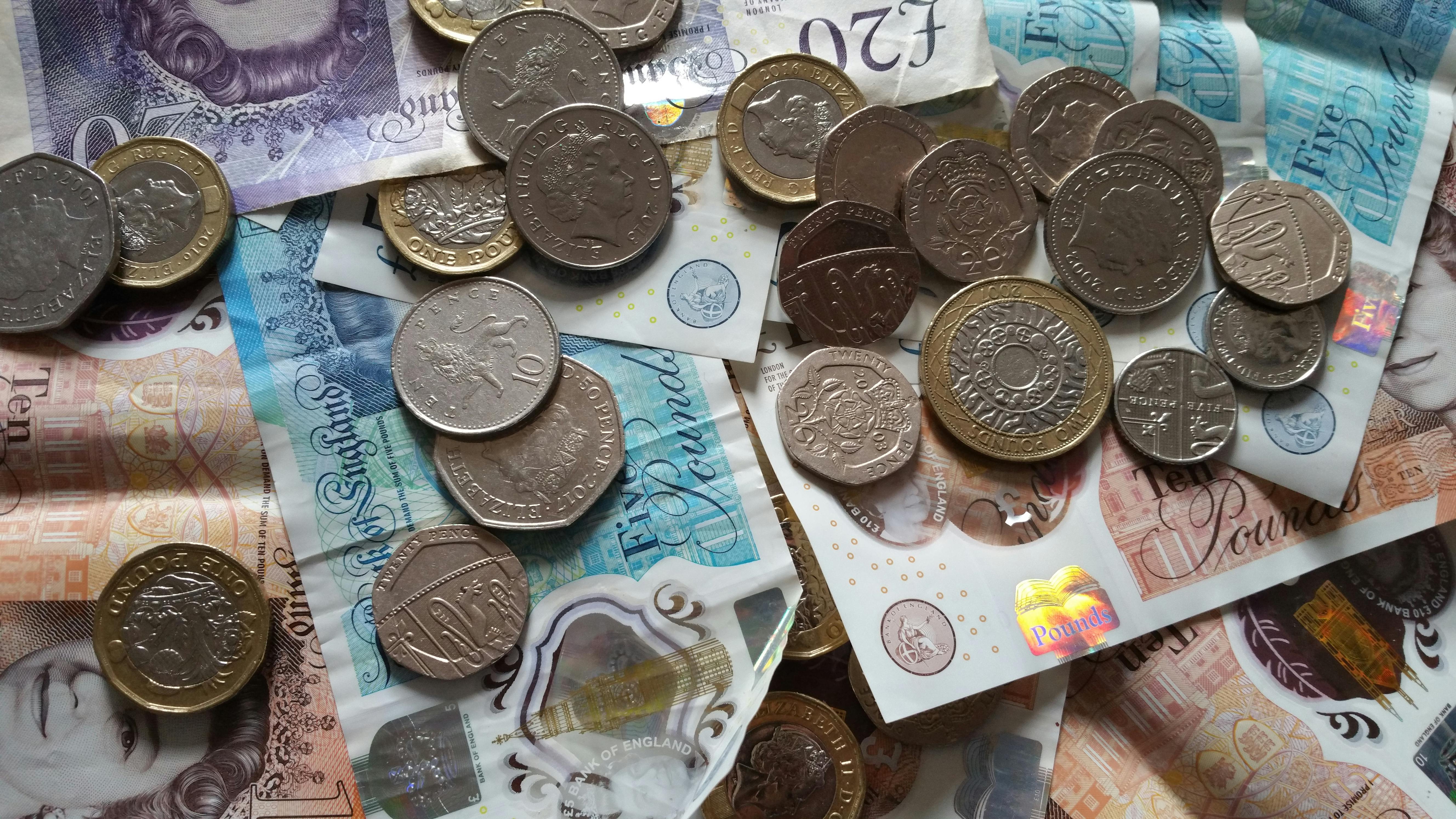 British banknotes and coins in a pile on a desk.