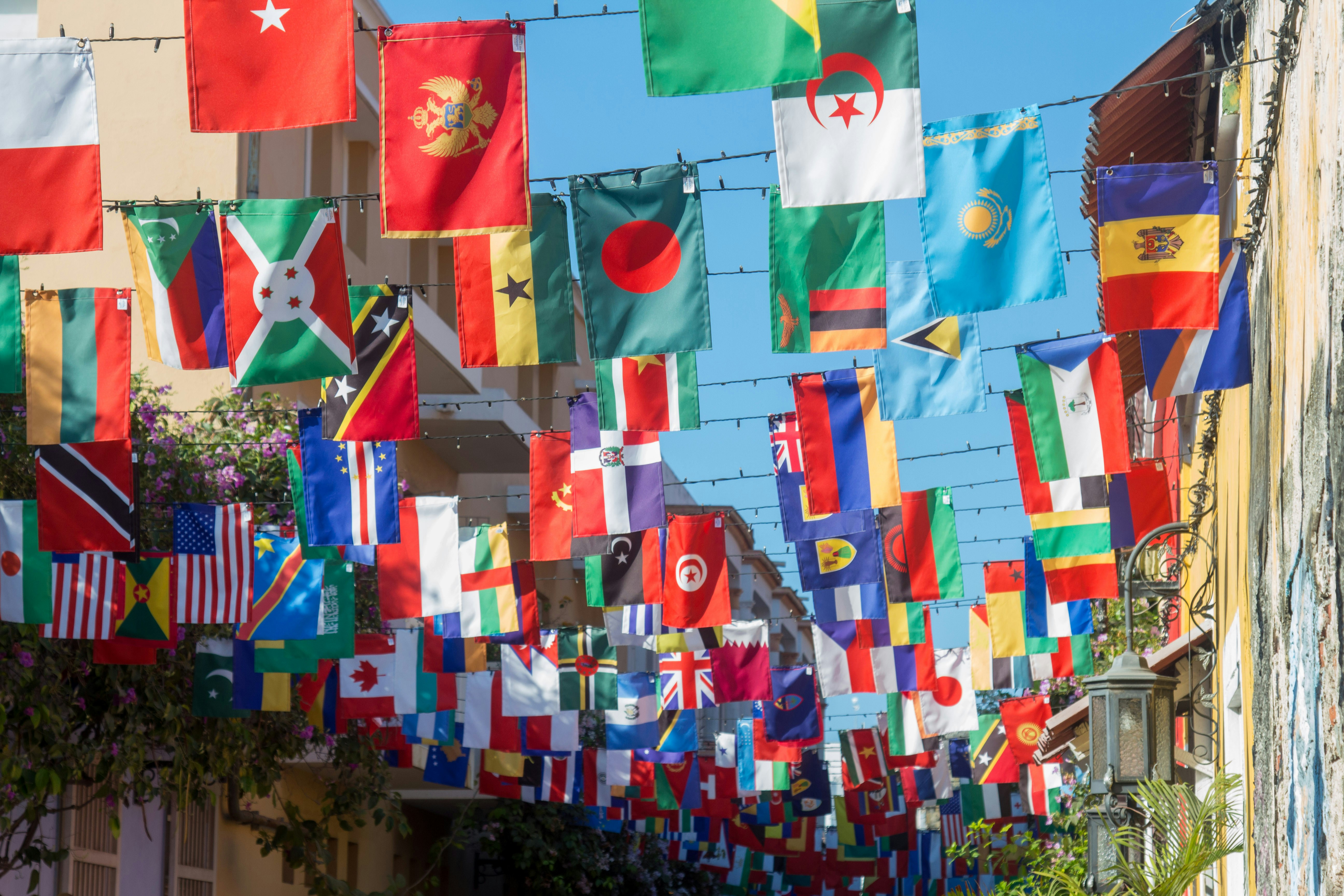 Lots of international flags being hung over a street.
