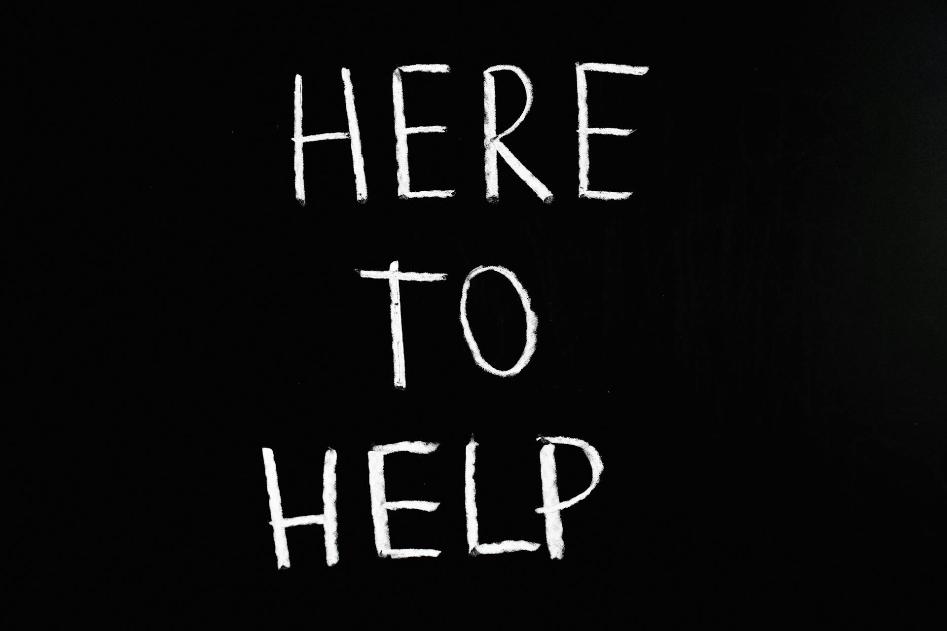 'Here to help' written in chalk on a blackboard.