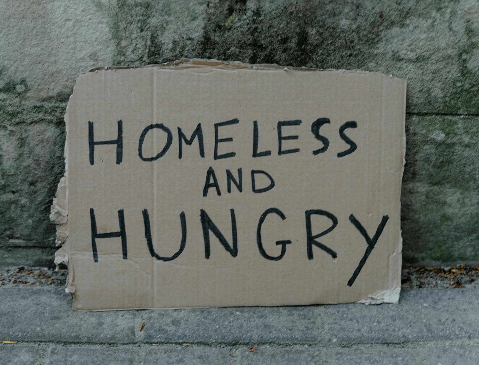 A sign on the street saying 'Homeless and hungry'.