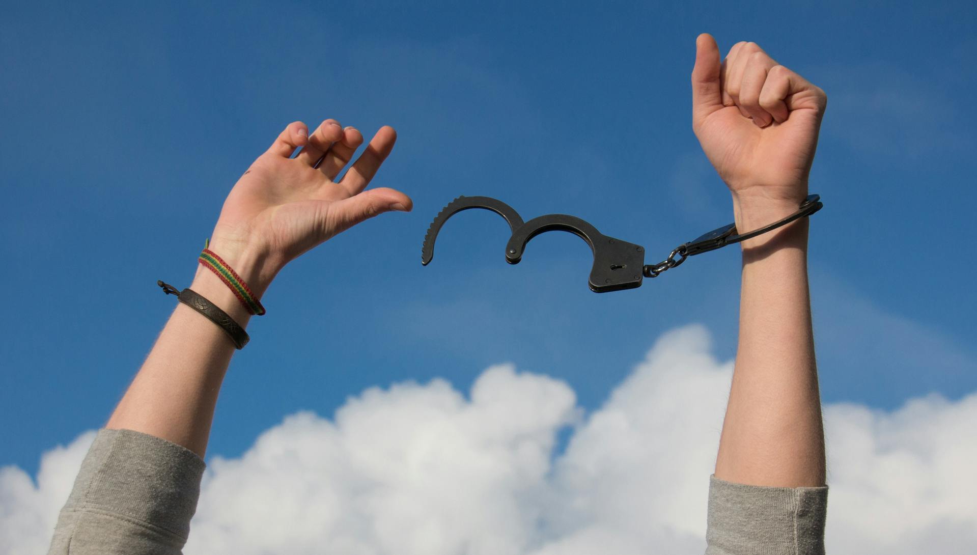 Hands in the air celebrating, with handcuffs broken off.