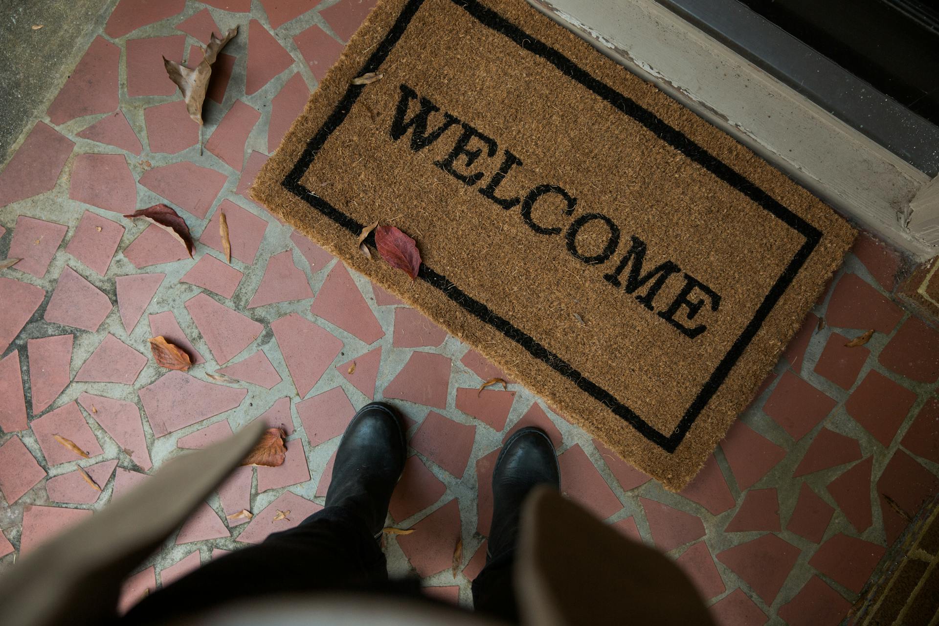 A mat saying 'Welcome' with a person standing above it.