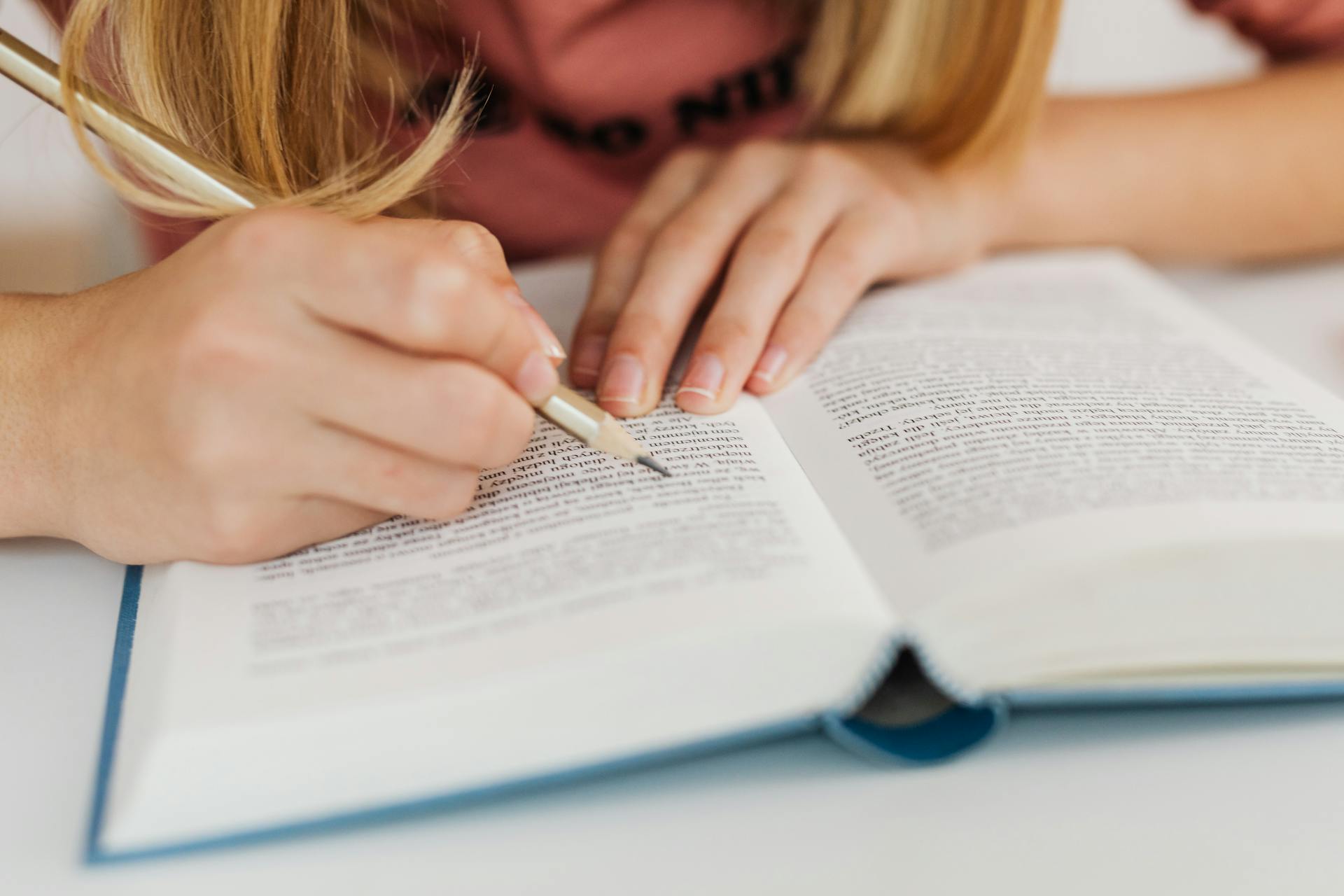 A close-up image of a woman reading a book at a desk.