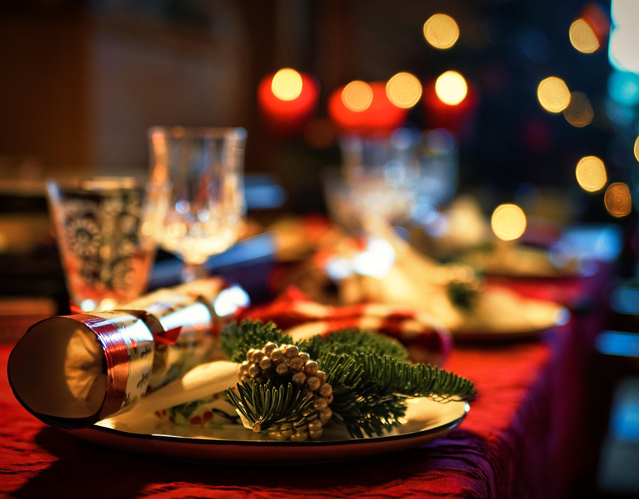 A Christmas table with glasses, plates and crackers.