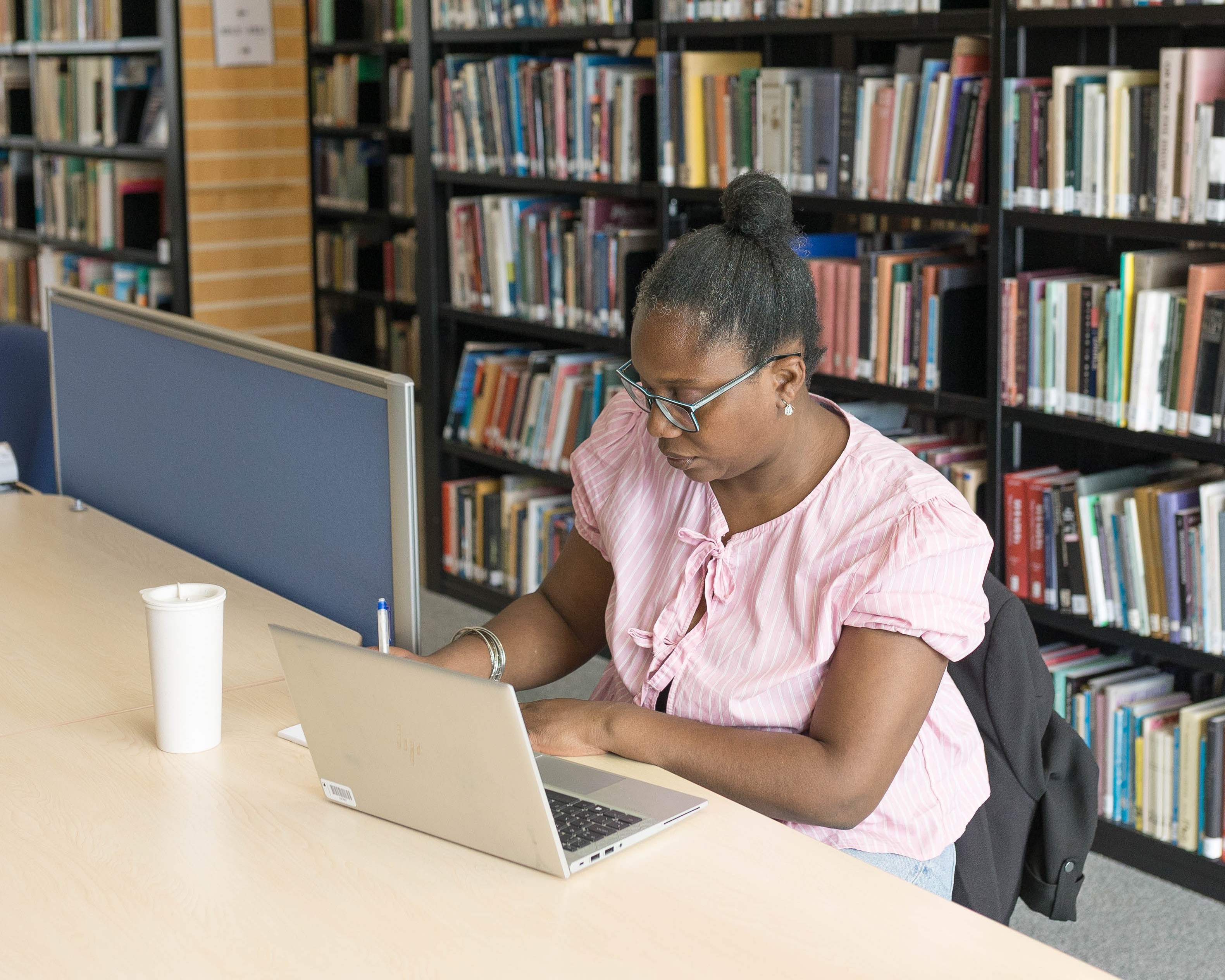 A woman sat at a table, working on a laptop.