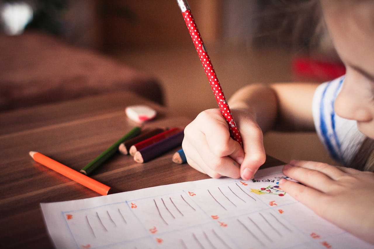 A child writing, sat at a table.